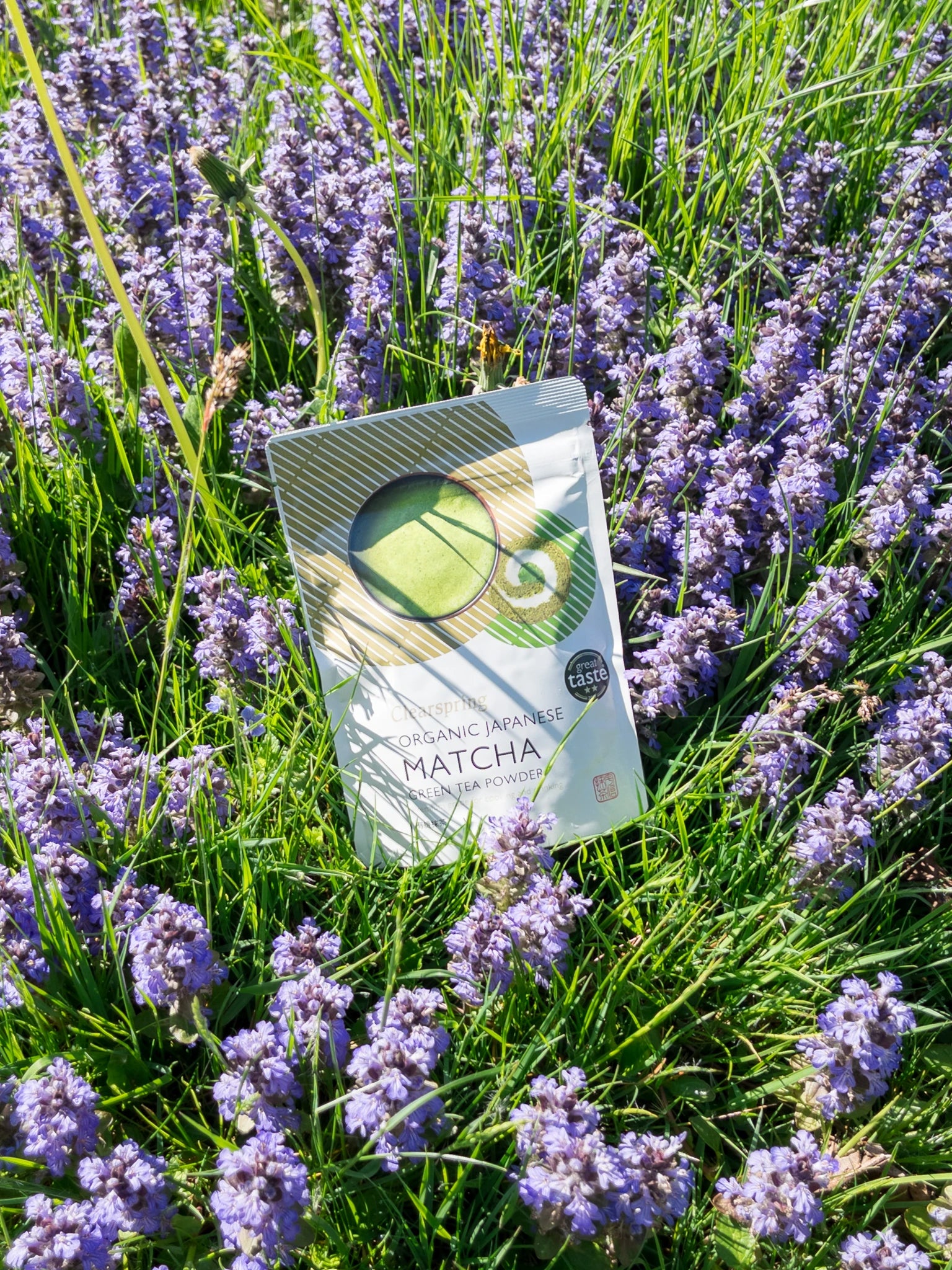 Sachet de thé Matcha Bio Premium Clearspring entouré de fleurs mauves | Eat in Japan Épicerie en ligne